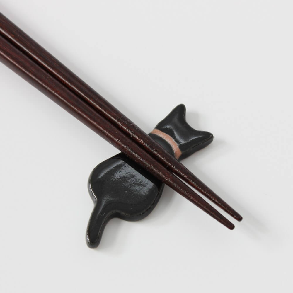 close up chopsticks tips on black cat rest