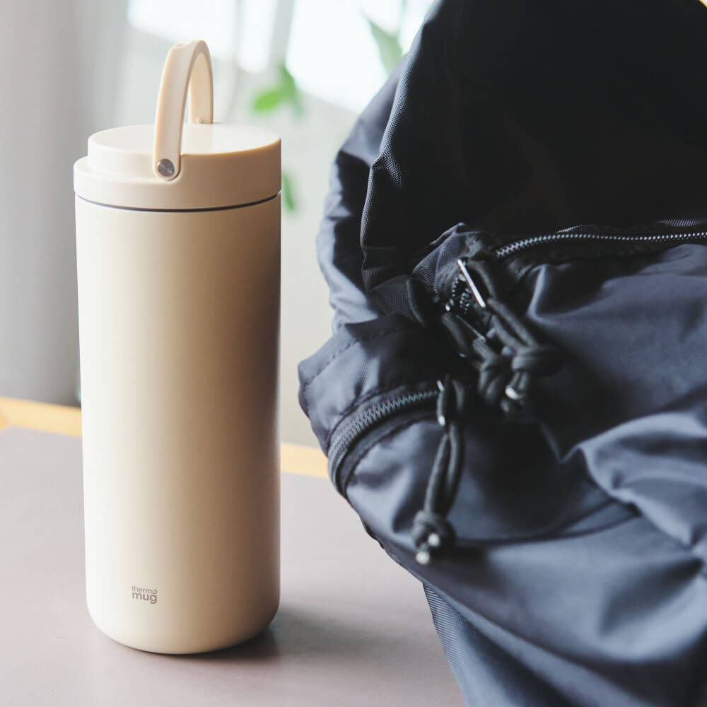 ivory lantern bottle next to a bag with handle up